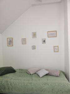 Bett in einem weißen Zimmer mit Bildern an der Wand in der Unterkunft L'escale CDG Astérix Park d'exposition in Louvres