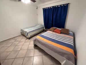 a bedroom with two beds and a blue curtain at Villa Rehobot in Contadora