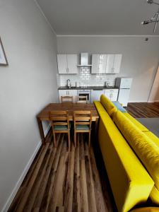 a kitchen with a yellow couch and a table and chairs at Lodging Młyńska Parking free in Bielsko-Biała