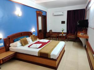 Habitación de hotel con cama con pared azul en Amruth Inn, en Guruvāyūr