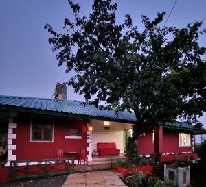 a red house with a red couch in front of it at Junglee Nest Holiday Home in Mahabaleshwar