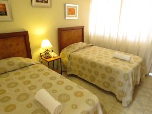 een hotelkamer met 2 bedden en een lamp bij Hotel Las Flores in Ica