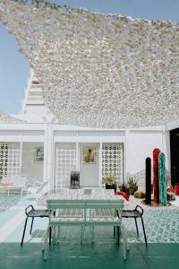 Casa blanca con una mesa en el patio en Hôtel Saint-Clair, côté Plage, en La Grande-Motte