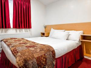 a bedroom with a large bed with red curtains at Royal Square Hotel - NEC & Birmingham Airport in Marston Green