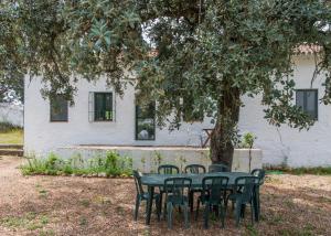einen Tisch und Stühle unter einem Baum vor einem Haus in der Unterkunft La Umbría de la Ribera in El Pedroso
