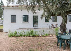 una mesa y sillas frente a una casa blanca en La Umbría de la Ribera, en El Pedroso