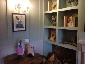 a room with a table with a fireplace and shelves at The Old Red Lion Inn in Cambridge