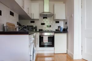 a kitchen with white cabinets and a stove at My Meadows, City Centre Apartment, Sunny&Spacious in Edinburgh