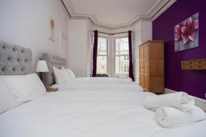 a bedroom with two white beds and a purple wall at My Meadows, City Centre Apartment, Sunny&Spacious in Edinburgh