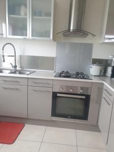 a white kitchen with a stove and a sink at chambre chez hôte 1 in Carbon-Blanc +5 photos