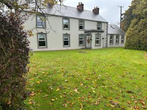 a large white house with a grass yard at Gortaclare Lodge in Beragh