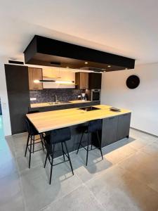 a kitchen with a wooden island with stools in it at Le gîte du Mawet in Léglise +7 photos