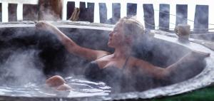 a man sitting in a hot tub filled with steam at Gîte Barn - Tirecul - 24 in Bergerac