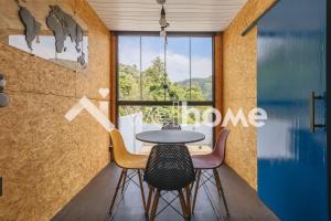 uma mesa e cadeiras num quarto com uma janela em Charmosa casa container em Águas de Lindóia em Águas de Lindóia