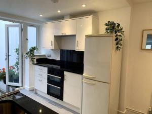 een keuken met witte kasten en een koelkast bij Newly refurbished Uplyme getaway in Uplyme