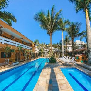 une piscine avec des palmiers à côté d'un immeuble dans l'établissement Pousada Acquaville PISCINA CLIMATIZADA, à Bertioga