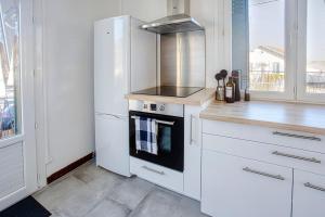 a white kitchen with a stove and a refrigerator at La Pause Douce Cosy à Angoulême - Confort, Lumière et Espace in Angoulême +14 photos