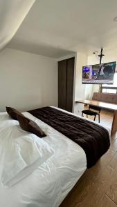 um quarto com uma grande cama branca e uma televisão em Origenes Apartments em Puerto Natales