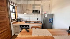 a small kitchen with a table and a refrigerator at Origenes Apartments in Puerto Natales
