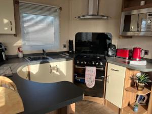 a small kitchen with a stove and a sink at Playa la Casa in Lossiemouth +7 photos