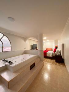 a large bathroom with a tub and a bedroom at Hotel Fontibon in Bogotá