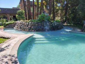 a swimming pool with a waterfall in a yard at Hotel Villa el Descanso in Curicó