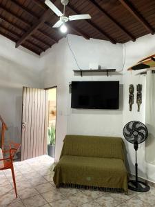 Un dormitorio con una cama y un televisor de pantalla plana en la pared. en Suítes Maresias, en Maresias