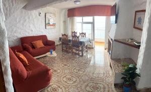sala de estar con sofá rojo y mesa en Casa Angelmar by Apartamentos Estrella del Norte, en Puerto de Santiago