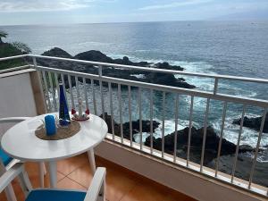 balcón con mesa y vistas al océano en Casa Angelmar by Apartamentos Estrella del Norte, en Puerto de Santiago