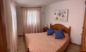 a bedroom with a bed with two blue pillows on it at Casa Angelmar by Apartamentos Estrella del Norte in Puerto de Santiago