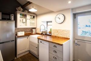 a kitchen with white cabinets and a clock on the wall at Cosy Cottage in Moreton-in-Marsh in Moreton in Marsh