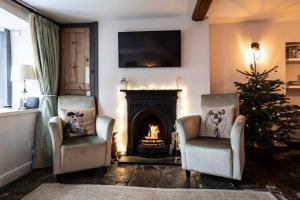 a living room with two chairs and a fireplace with a christmas tree at Cosy Cottage in Moreton-in-Marsh in Moreton in Marsh