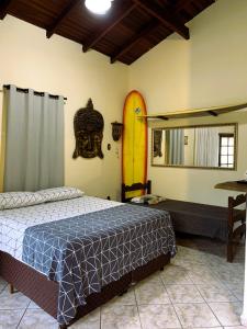 Un dormitorio con una cama y una tabla de surf en la pared. en Suítes Maresias, en Maresias