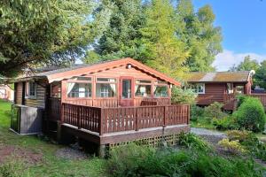 een houten hut met een terras in een tuin bij 299 Willow Lodge in Trawsfynydd
