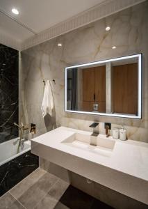 ein Badezimmer mit einem Waschbecken, einem Spiegel und einer Badewanne in der Unterkunft Deluxe Apartment in Taschkent