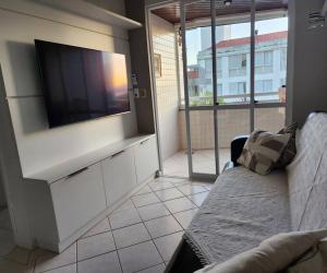 Apartamento pe na areia e com vista linda في فلوريانوبوليس: غرفة معيشة مع تلفزيون بشاشة مسطحة وأريكة