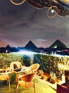 una mesa y sillas en un patio con montañas al fondo en Eyad Pyramids view, en El Cairo