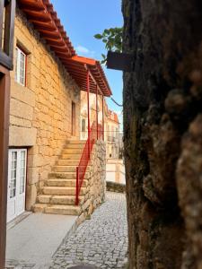 un edificio de piedra con escaleras y barandilla roja en Casa da Vila - Apartamento rés chão, en Alpedrinha