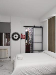 マドリードにあるMalasaña Palma Studiosの白いベッドと壁に時計が備わるベッドルーム1室が備わります。