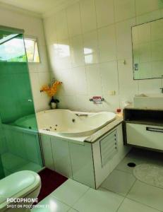 uma casa de banho com uma banheira, um lavatório e um WC. em Pousada Marcos no Guarujá
