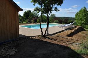 una piscina con 2 tumbonas junto a un edificio en Gîte pour 4 personnes - Dordogne, en Bressac