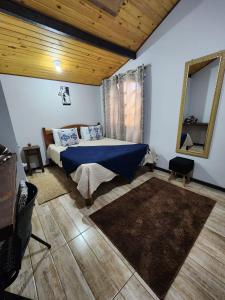 Un dormitorio con una cama y un espejo en la pared. en Chalés Juliana Casa 1, en Monte Verde