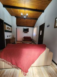 um quarto com uma cama grande e um cobertor vermelho em Chalés Juliana Casa 1 em Monte Verde