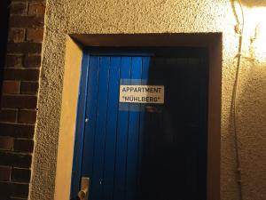 ein Schild an einer blauen Tür mit einem Schild darauf in der Unterkunft Appartment Mühlberg Obermühle in Kirchensittenbach