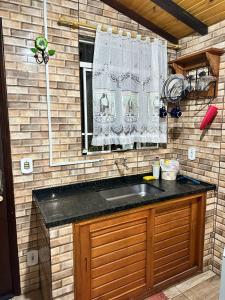 una cocina con fregadero y ventana en Chalés Juliana Casa 1, en Monte Verde