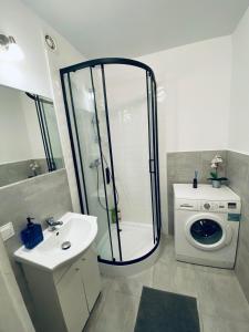 a bathroom with a shower and a washing machine at ClickTheFlat Wokalna Apart Rooms in Warsaw