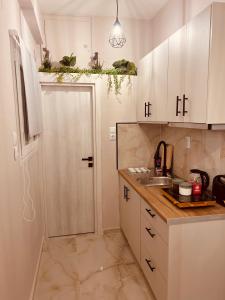 cocina con armarios blancos, fregadero y puerta en Cactus Luxury suite2, en Atenas