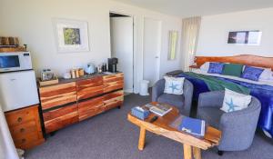 a bedroom with a bed and a chair and a table at View With A Room NZ - Boutique Beachfront Accommodation on the Great Coast Road in Runanga