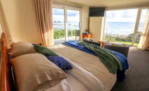 a bedroom with a bed with a view of the ocean at View With A Room NZ - Boutique Beachfront Accommodation on the Great Coast Road in Runanga