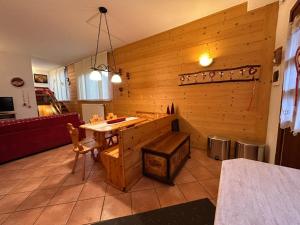 a kitchen with a wooden wall with a table and chairs at La tana del lupo in Camporosso in Valcanale